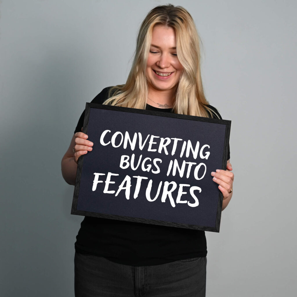 Spaßbild. Lilly Seiffert hält ein Schild mit der Aufschrift: Converting bugs into features