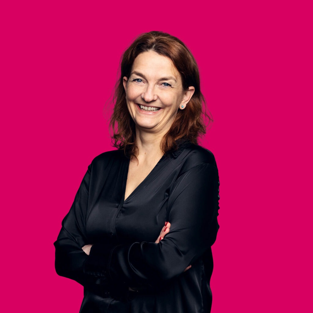 Digital Process Managerin Nicole Köhler-Betker lächelt mit verschränkten Armen in die Kamera