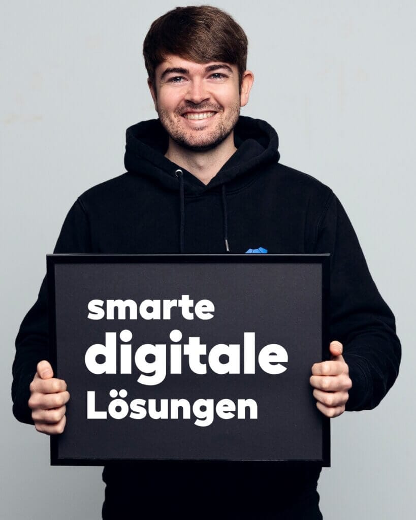 Ein lächelnder Mitarbeiter hält ein Schild mit der Aufschrift „Smarte digitale Lösungen“.
